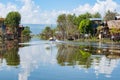 Inle Lake locals motoring in small boat up channel between homes of floating village