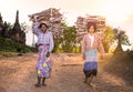 Burmese women carrying a bundle of heavy wood wearing traditional clothing in Indein village , Myanmar.