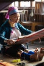 Inle, Myanmar - March 2019: Kayan Lahwi tribe long neck woman sits behind the loom