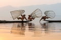 Inle, Myanmar - March 2019: three traditional Burmese leg rowing fishermen at Inle lake