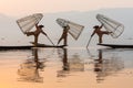 Inle, Myanmar - March 2019: three traditional Burmese leg rowing fishermen at Inle lake