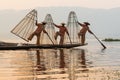 Inle, Myanmar - March 2019: three traditional Burmese leg rowing fishermen at Inle lake