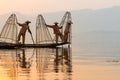 Inle, Myanmar - March 2019: three traditional Burmese leg rowing fishermen at Inle lake