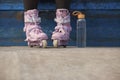 Young skater girl sitting on a ledge in a skatepark with glass water bottle. Feet of unrecognizable female roller blader wearing