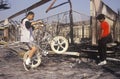 Inner city youth riding bicycle at burned out building, South Central Los Angeles, California