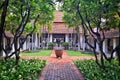 Inner courtyard of a traditional Lanna northern Thai mansion with green plants and trees lining the walkways.