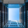 Inner yard of modern office building looking upwards through square opening into blue sky at noon Royalty Free Stock Photo