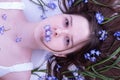 Innocent girl lies in hair tangled blue spring flowers