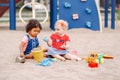 Caucasian and hispanic latin babies children sitting in sandbox playing with plastic colorful toys Royalty Free Stock Photo