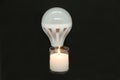 The innovation is a candle and new economical light bulbs on a black background