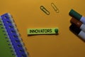 Innovators write on sticky notes. Isolated on orange table background