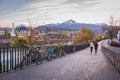 Innsbruck embankment with bicycles and unknown walking people. Innsbruck landmark with mountains on background.