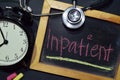 Inpatient handwriting on chalkboard on top view. Alarm clock Royalty Free Stock Photo