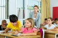 Inquisitive preteen boy peeking at workbook of cute smiling girl in class Royalty Free Stock Photo