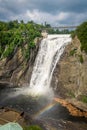 Cloudy summer day with insane view of beautiful and powerful Montmorency waterfall with a rainbow in front