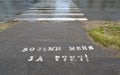 Inscription on asphalt in Russian Take me by hand!`. Crosswalk