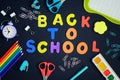 Inscription Back to school in colorful letters in the center of the black background. Color pencils, watercolor paints Royalty Free Stock Photo