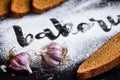 Inscription bakery on white wheat flour scattered Sliced rye bread with garlic on dark background