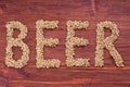 The inscription of beer by malt grains on wood background. Craft