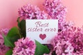 inscription best sister ever on a white gift card in a beautiful spring bouquet of lilac