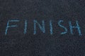 Inscription on black asphalt - FINISH. Word written with chalk on pavement