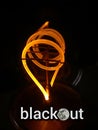 The inscription blackout on the background of a spiral light bulb on a dark background Royalty Free Stock Photo