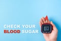 Inscription check your blood sugar,red blood drop,Blood glucose test strips,Glucose meter in man hand on blue background Royalty Free Stock Photo