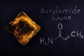 inscription chemical formula of acrylamide and black burnt bread toast containing acrylamide on a black background