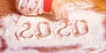 Inscription 2020 with a children`s hand on a flour board new year background, birth, childbirth, happiness - concept