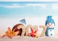 Inscription 2017, coconut, starfish, flower, snowman in sand against sea. Royalty Free Stock Photo