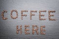 The inscription Coffee here is lined with coffee beans. Rough grey stone background Royalty Free Stock Photo