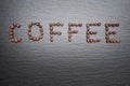 The inscription Coffee is lined with coffee beans. Rough grey stone background Royalty Free Stock Photo