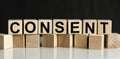 The inscription CONSENT on wooden cubes isolated on a dark background, the concept of business and finance