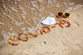 Inscription Covid-19 made of amber stones, protective mask and sunglasses on sand at beach. Safe holidays Royalty Free Stock Photo