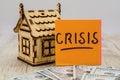 The inscription `crisis` on the sticker, dollars and a small wooden house. The concept of crisis, rising or falling real estate pr Royalty Free Stock Photo