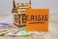 The inscription `crisis` on the sticker, Ukrainian hryvnia and a small wooden house. The concept of crisis, rising or falling real Royalty Free Stock Photo