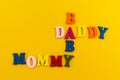 The inscription `Daddy, Mommy, Baby` in colorful letters on a yellow background
