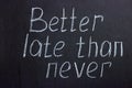 The inscription on the dark board `Better late than never`