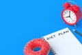 Inscription diet plan on notepad near donut, pencil, alarm clock