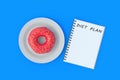 Inscription diet plan on notepad near donut on plate