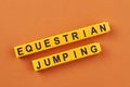 The inscription equestrian jumping written on yellow cubes against color background.