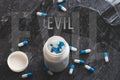 The inscription evil on the background of pills on a black table. Royalty Free Stock Photo