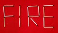 Inscription fire from matches. The word fire is laid out from matches on a red background. Royalty Free Stock Photo