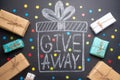 The inscription Giveaway is written on a blackboard with gifts. Free distribution, bloggers and gifts