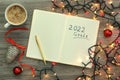 Inscription 2022 Goals written in planner, cup of coffee and Christmas decor on wooden background, flat lay. New Year aims Royalty Free Stock Photo