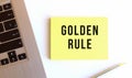 The inscription GOLDEN RULE on the yellow sticky notes on the white office desk.