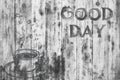 The inscription `Good day` on a gray texture of wood. Have a good day. A cup of coffee.