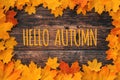 Inscription Hello Autumn on a wooden background with a frame of orange maple leaves Royalty Free Stock Photo