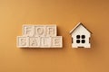 The inscription house for sale made of wooden cubes on an orange background. The concept of selling a house or apartment