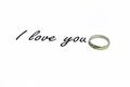 Inscription I love you on a white background. Behind the text a gold ring with stones.